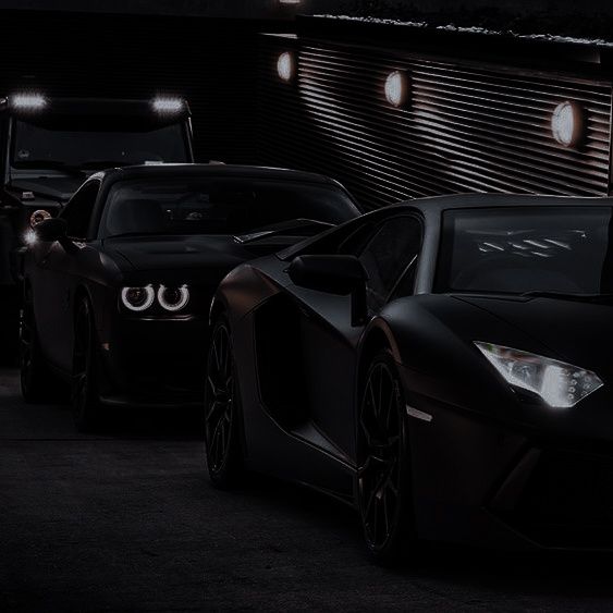 three black sports cars parked side by side in the dark