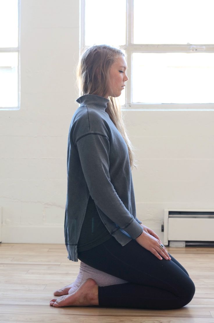 a woman is sitting on the floor doing yoga