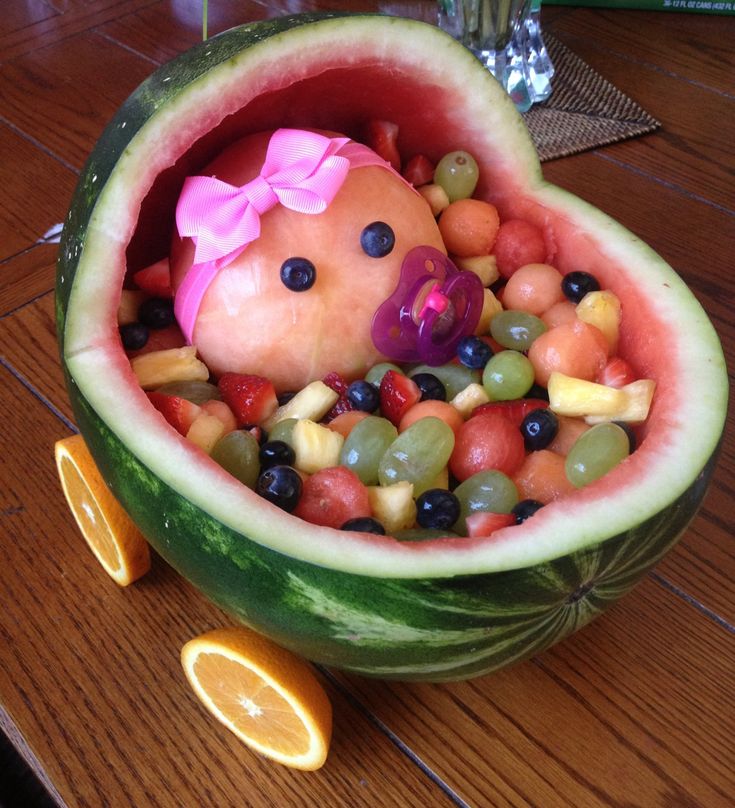 a watermelon shaped like a baby in a pile of fruit