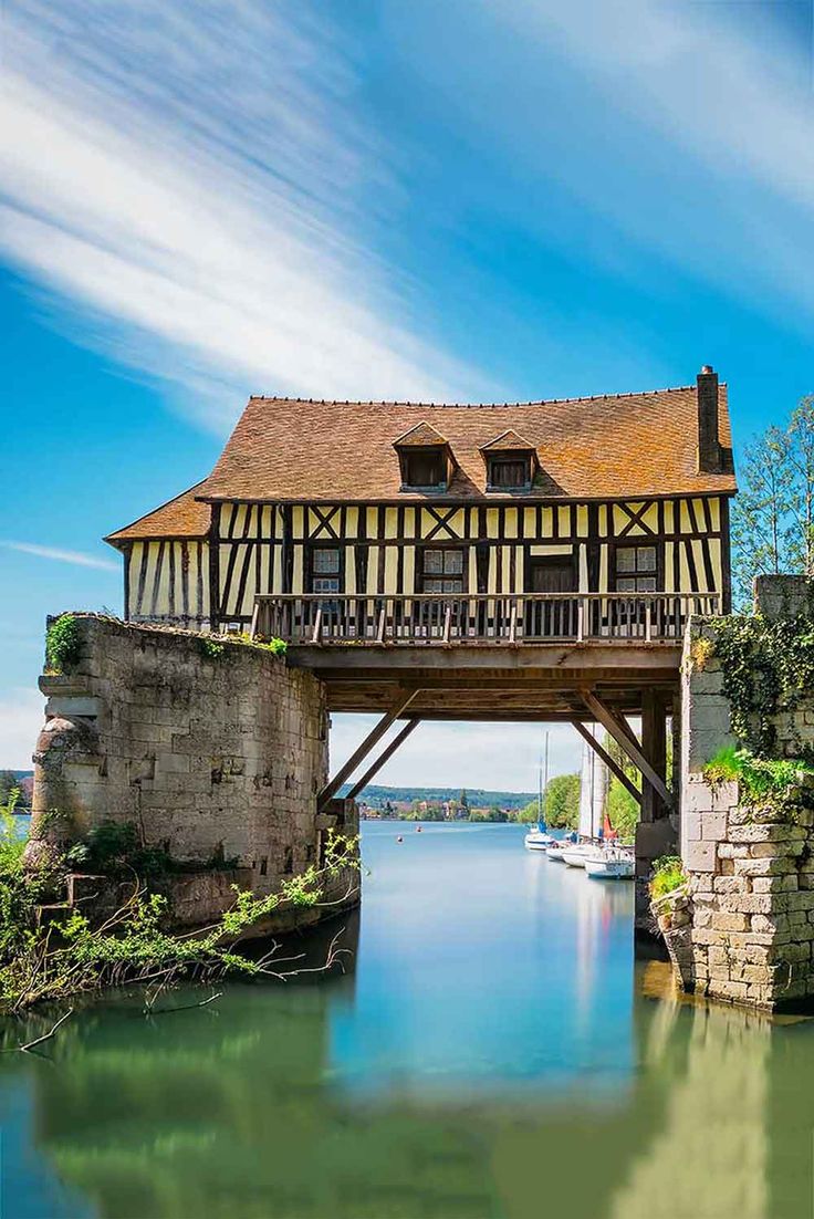 an old bridge over a body of water with a boat in the river below it