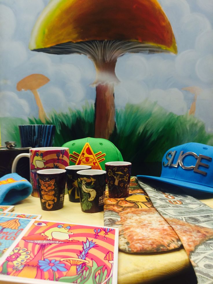 there are many cups on the table with different pictures and hats around it, including a mushroom