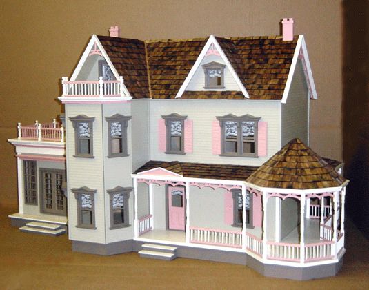 a doll house with pink shutters on the front and brown shingles on the roof