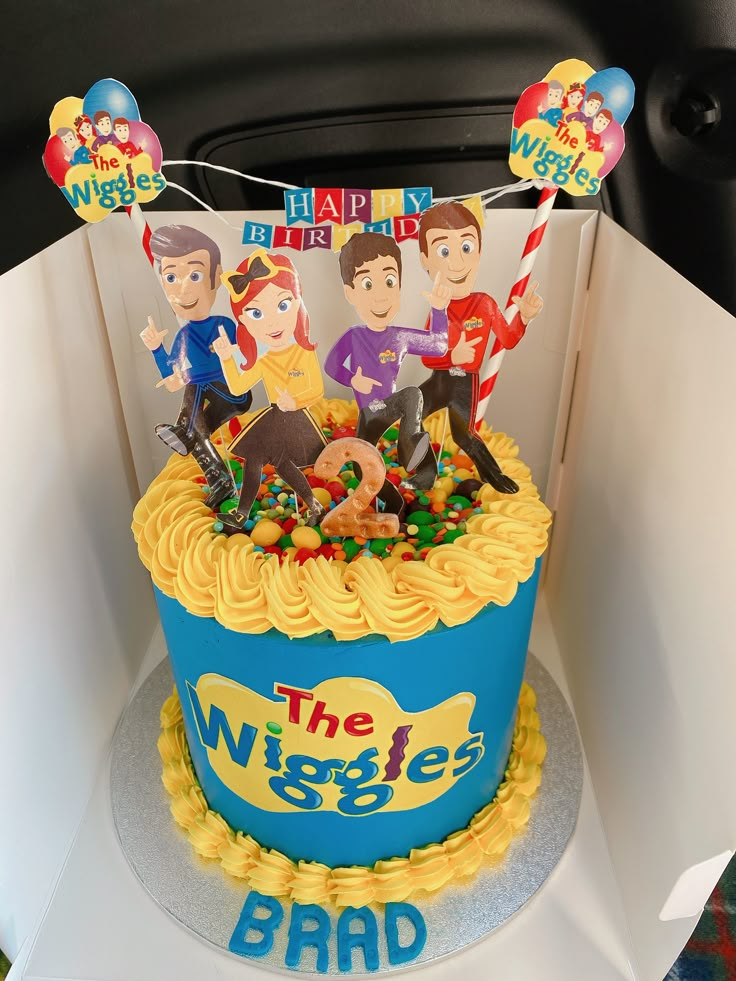 a birthday cake with the wiggles on it is in a box for someone's birthday