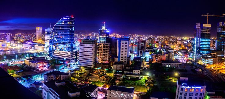 an aerial view of a city at night with tall buildings and bright lights in the foreground