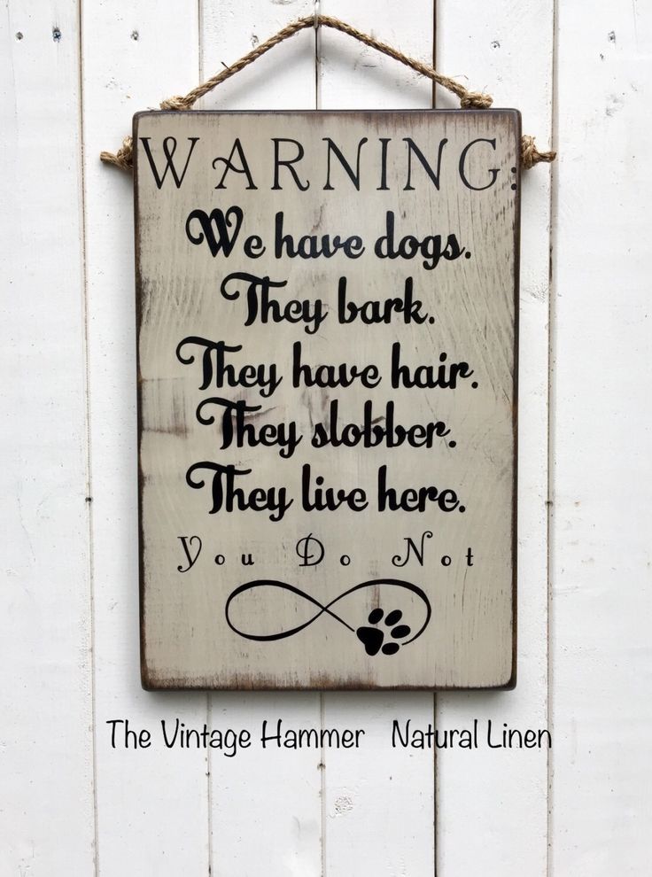 a wooden sign hanging on the side of a white wall with an image of a dog's paw