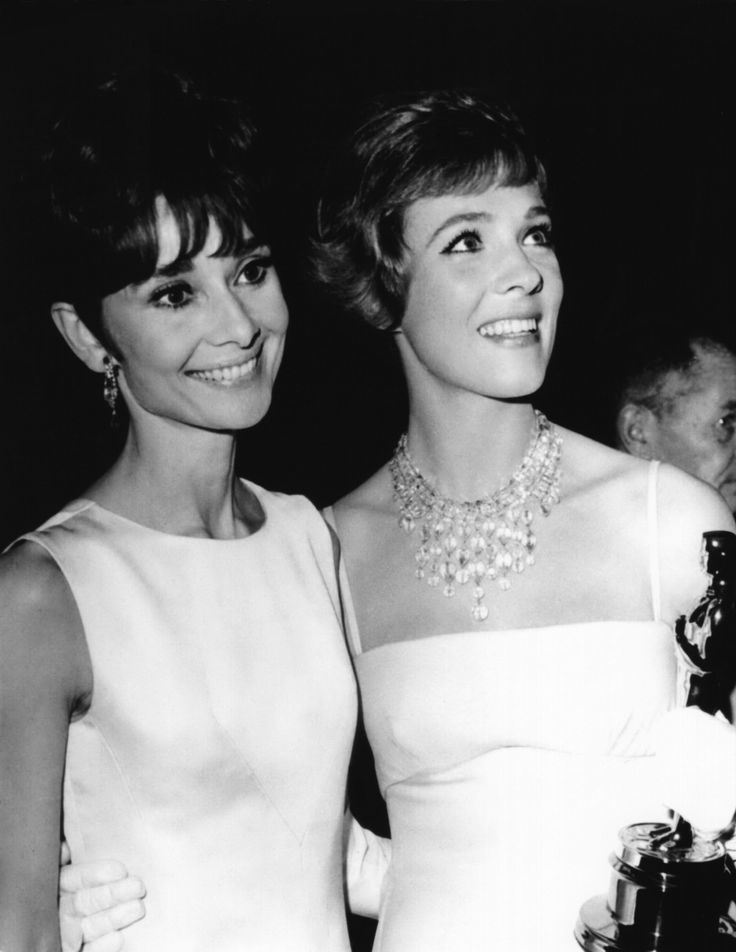 two women standing next to each other holding an oscar award in front of their faces