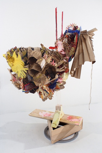 a sculpture made out of paper on top of a wooden box with scissors and other items hanging from it