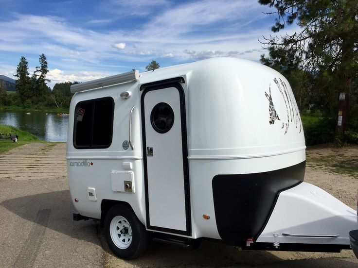 a white trailer parked next to a lake