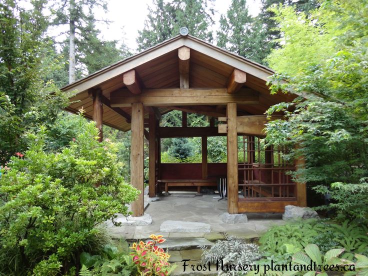 a wooden gazebo surrounded by lush green trees