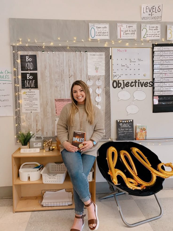 a woman sitting on a chair holding a book in front of a desk with gold letters