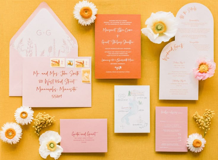 the wedding stationery is laid out on top of each other, including pink and white flowers