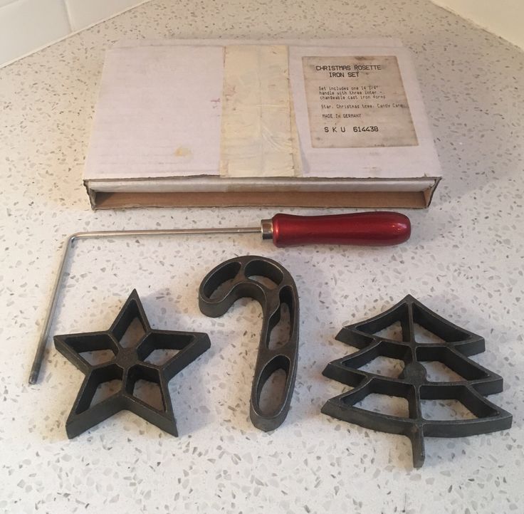 the cookie cutters are next to some christmas tree shaped cookie cutters and an open book