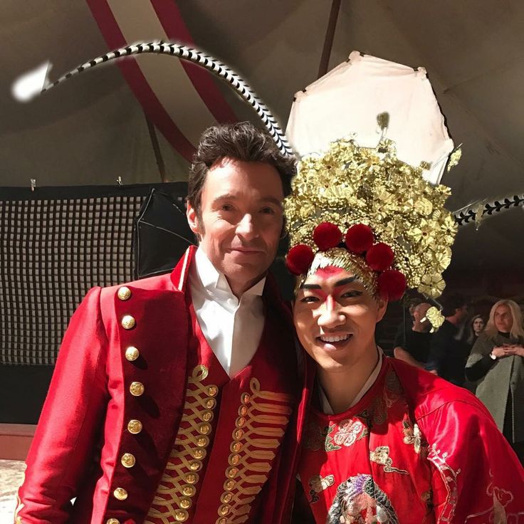 two men dressed in red and gold standing next to each other at a carnival event