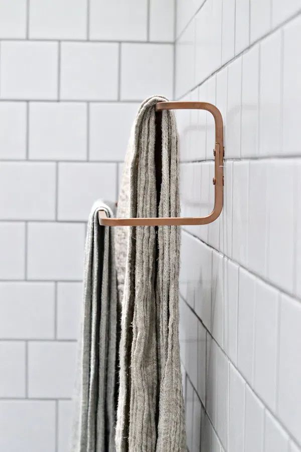 a towel rack in the corner of a bathroom with white tile walls and flooring