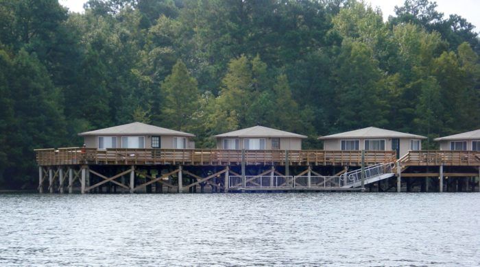 several cabins are on the water near some trees