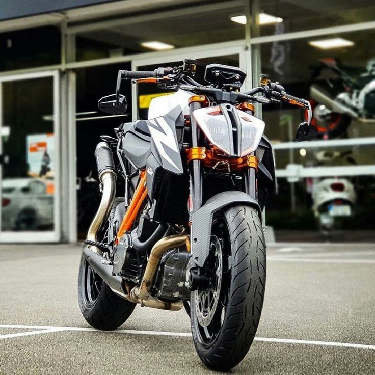 an orange and white motorcycle parked in front of a building