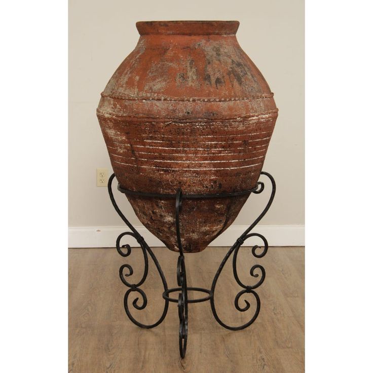 an old urn sitting on top of a metal stand in the corner of a room