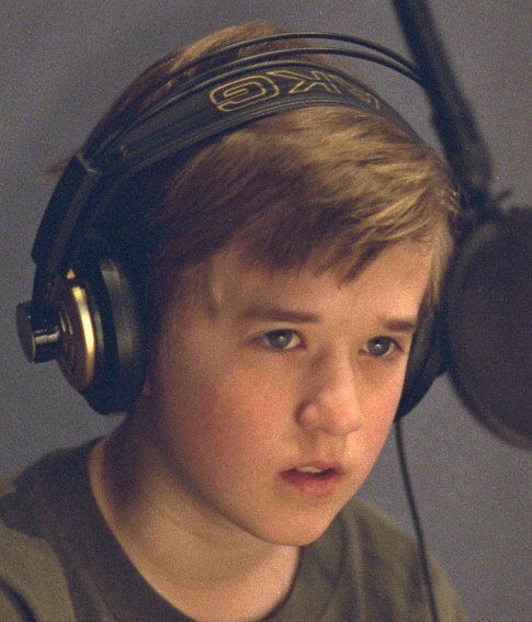 a young boy wearing headphones in front of a microphone