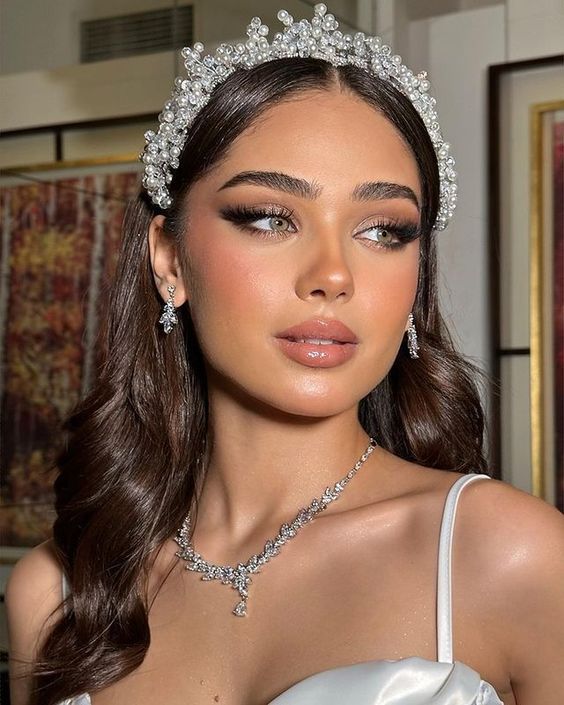 a woman in a white dress wearing a tiara and diamond necklace with pearls on her head