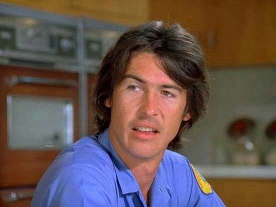 a man wearing a blue shirt and tie in a kitchen