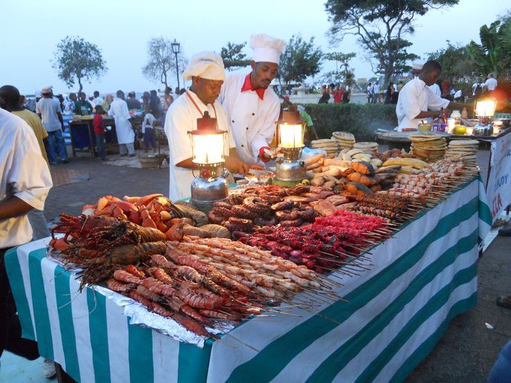 several people standing around a table with food on it and lit candles in front of them