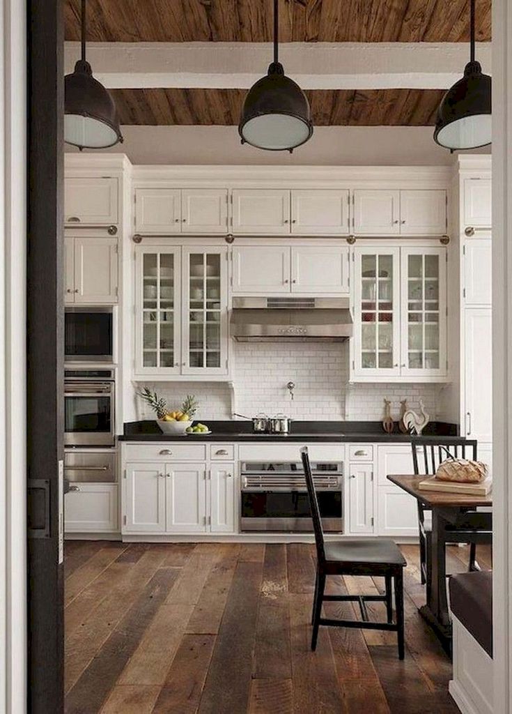 an open door leading to a kitchen with white cabinets and wood flooring on the walls