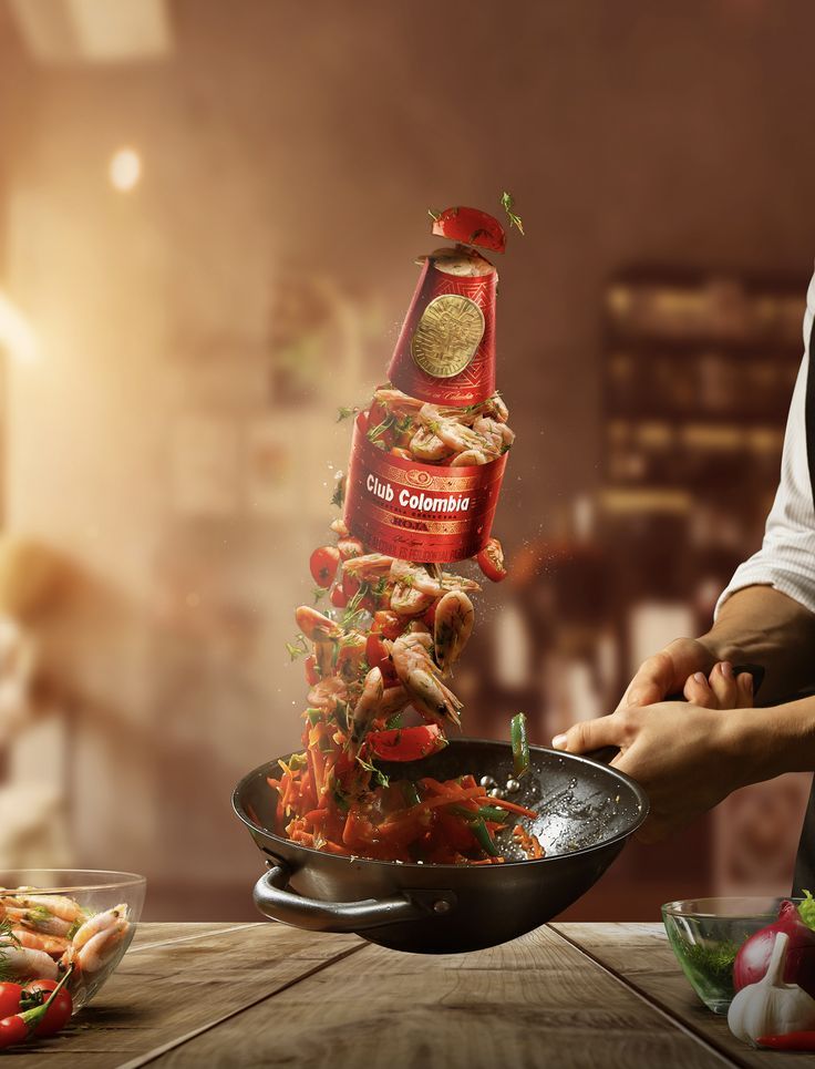 a person cooking food in a frying pan on a wooden table next to other foods