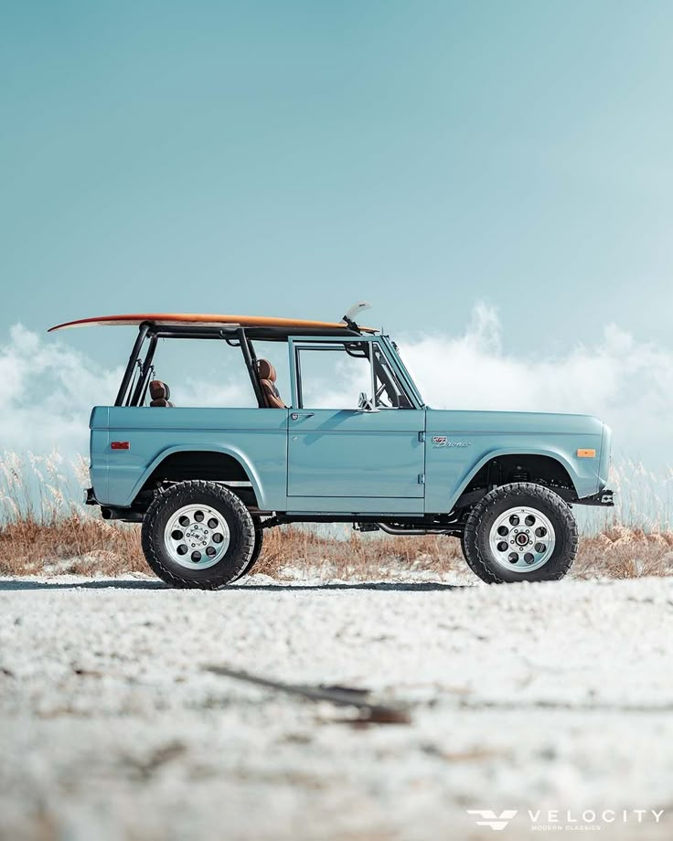 a blue truck with a surfboard on top of it's roof