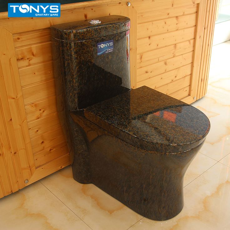 a toilet that is sitting in the middle of a floor next to a wooden wall