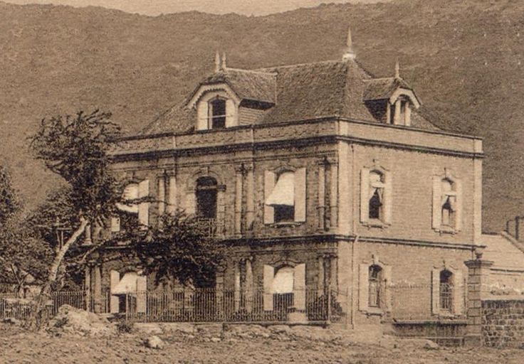 an old photo of a house with mountains in the background