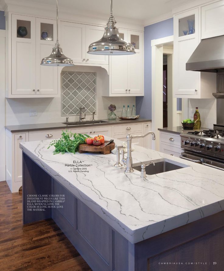 a kitchen with white cabinets and an island in the middle of the room is lit by two pendant lights