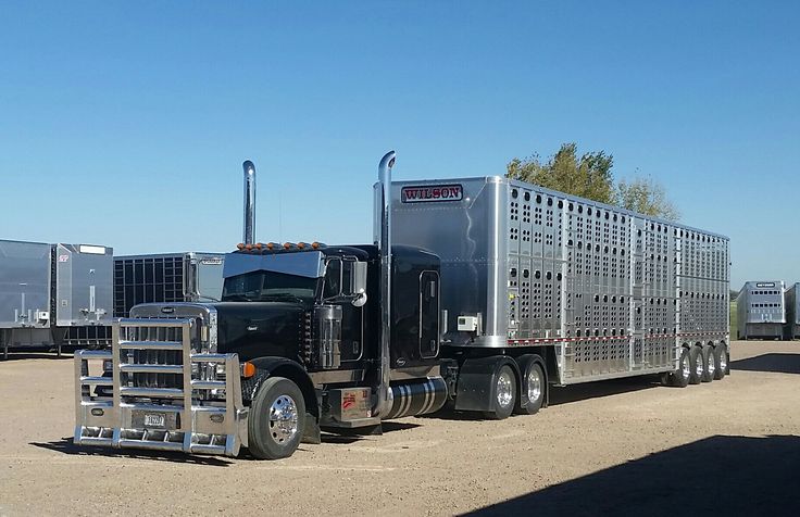 a large semi truck parked on the side of a dirt road in front of other trailers