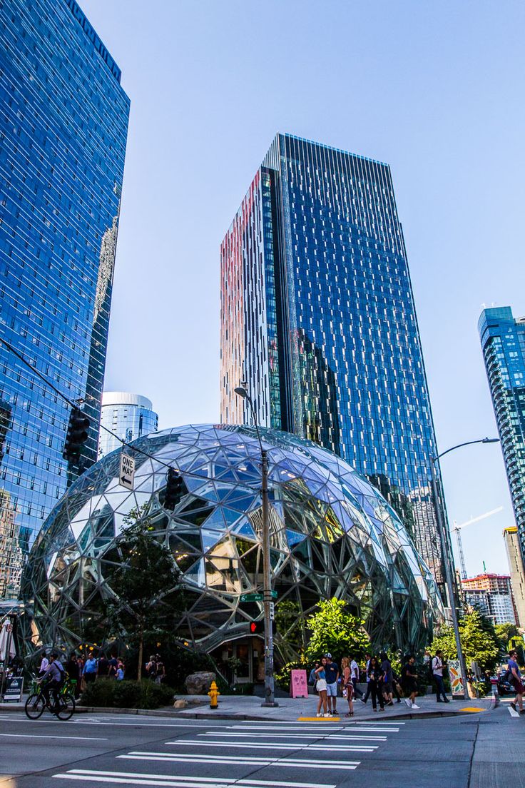 people crossing the street in front of some very tall buildings with glass domes on them