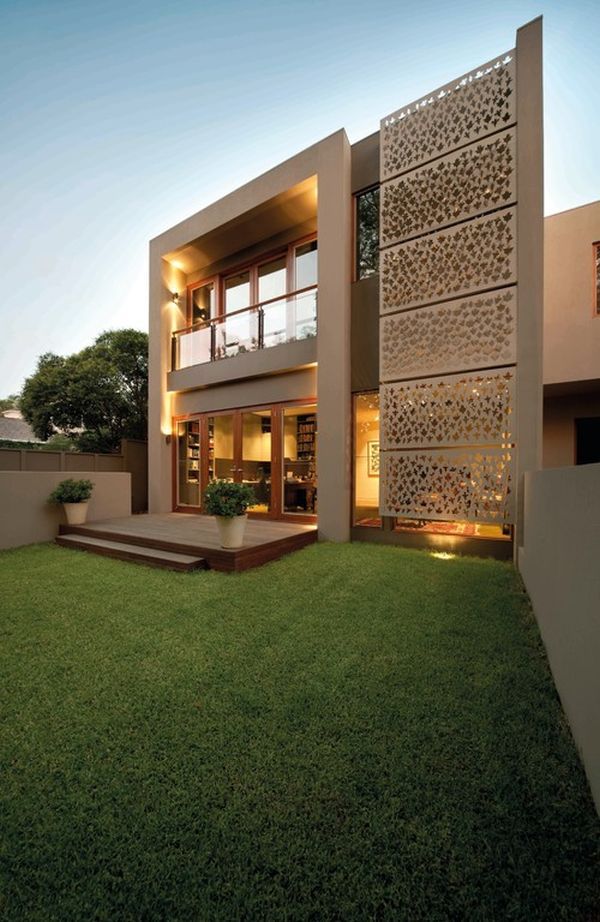 a modern house with grass in front and stairs leading up to the upper floor area