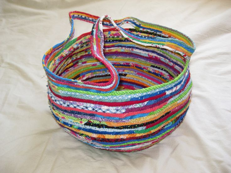 a multicolored basket sitting on top of a white sheet