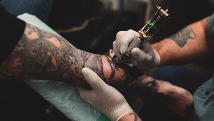 a man getting his arm tattoo done by someone with tattoos on their arms and hands