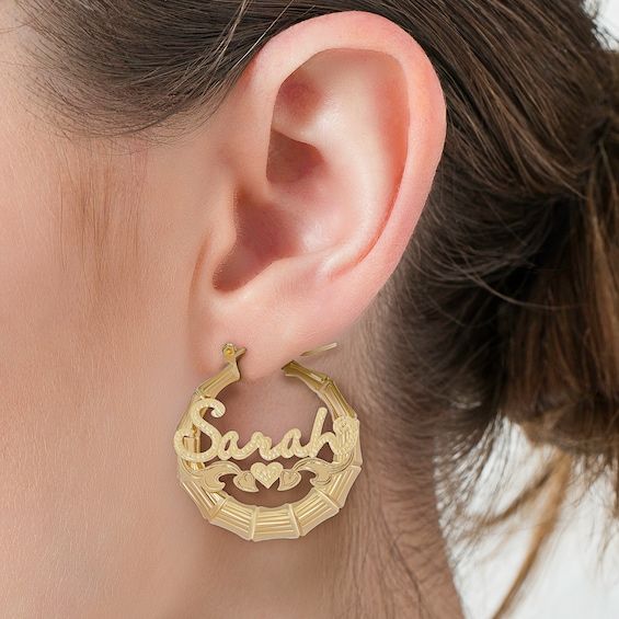 An alluring look with personalized details, these hoop earrings draw all the right kinds of attention. Created in 14K gold over silver, each tapered hoop features a unique bamboo-textured design. Across the center, the name of your choice - from three to 10 characters in length - is sculpted in a script font and set atop a heart. Filigree ribbons and a pair of heart-shaped leaf details complete the style. Polished to a bright shine, these hoop earrings secure with latch backs. Elegant Personalized Hoop Jewelry, Personalized Elegant Hoop Jewelry, Small Hoop Engraved Earrings, Engraved Small Hoop Earrings As Gift, Engraved Small Hoop Earrings For Gift, Small Hoop Engraved Yellow Gold Earrings, Engraved Small Hoop Earrings In Yellow Gold, 14k Gold Pierced Hoop Earrings Gift, Elegant Personalized Huggie Earrings