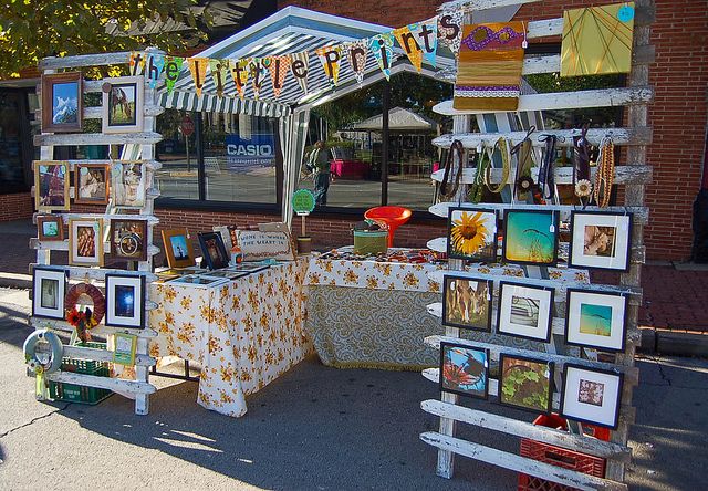 an outdoor booth with pictures and decorations on it's display stand, along side a brick building