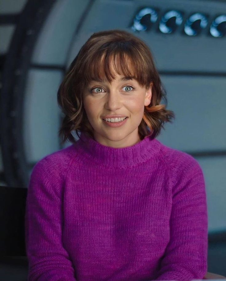 a woman wearing a purple sweater is smiling at the camera