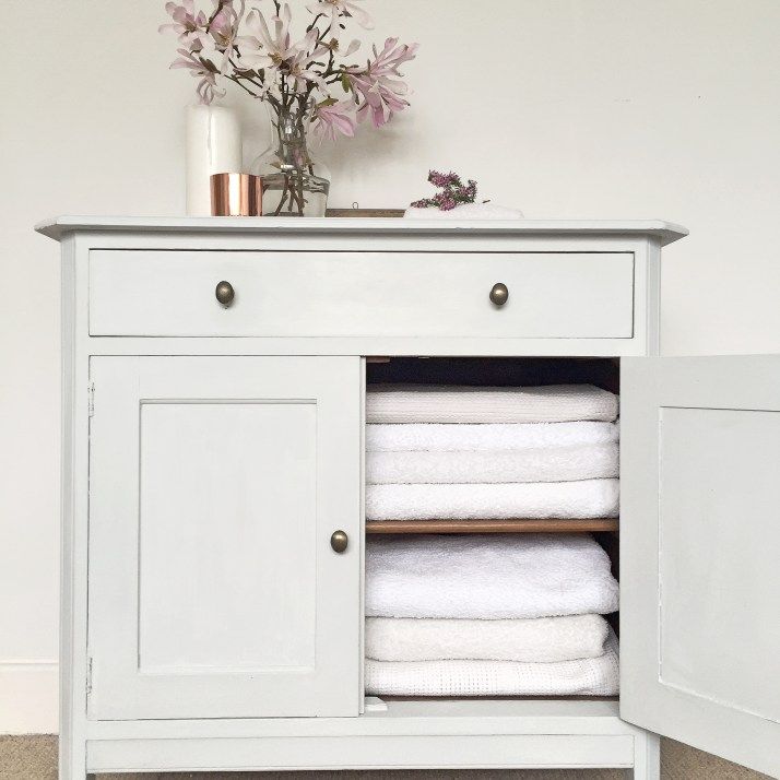 a white cabinet with towels and flowers on top