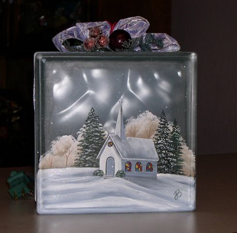 a glass block with a house in the snow and trees under it, on top of a table