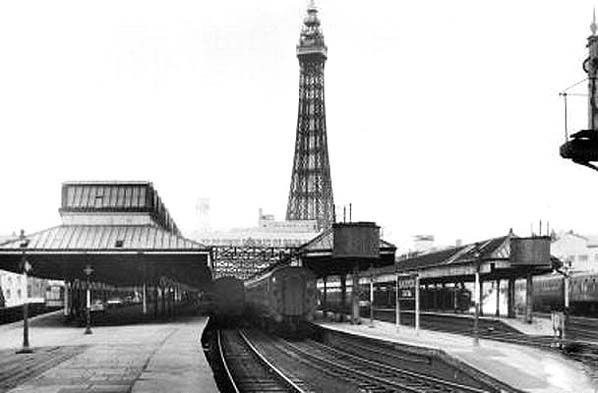 a black and white photo of a train station with the eiffel tower in the background