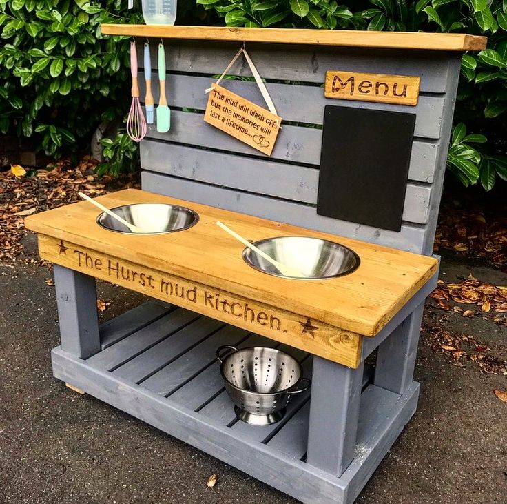 an outdoor kitchen made out of pallet wood with two bowls on the top and one bowl at the bottom