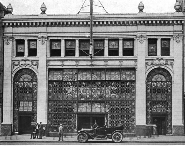 an old black and white photo of people standing in front of a building with ornate glass windows