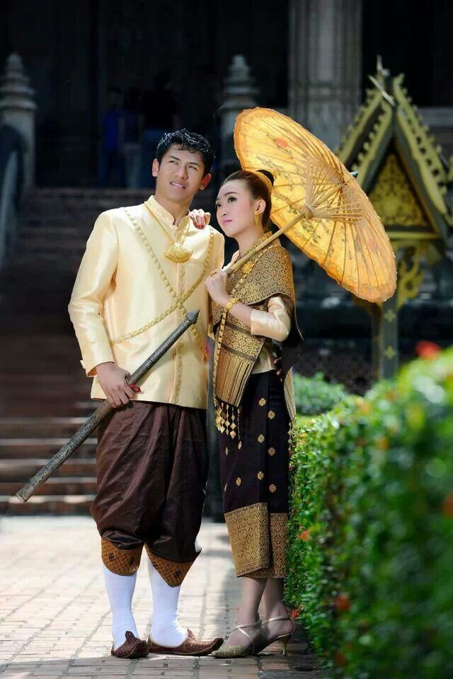 a man and woman standing next to each other with an umbrella on their head in front of a building