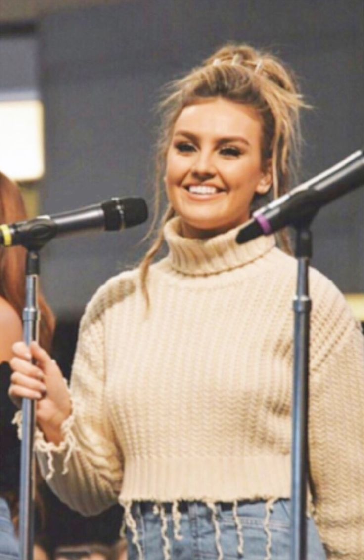 two women standing in front of microphones with one holding a microphone and the other singing