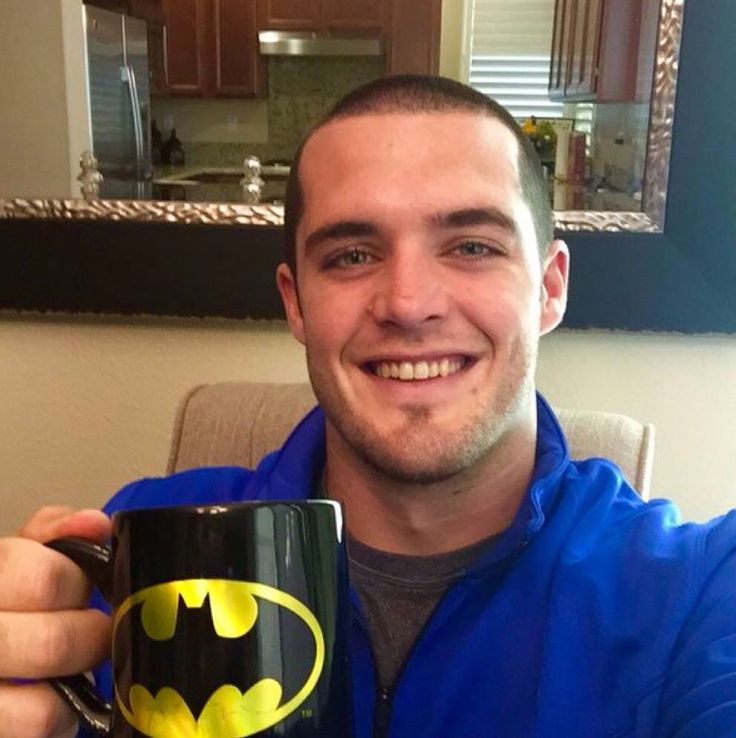 a man in a blue jacket holding a batman mug