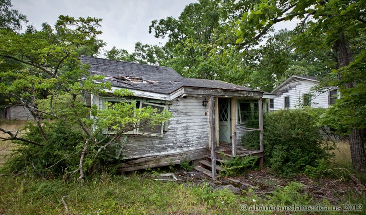 an old run down house sitting in the middle of a field with trees around it