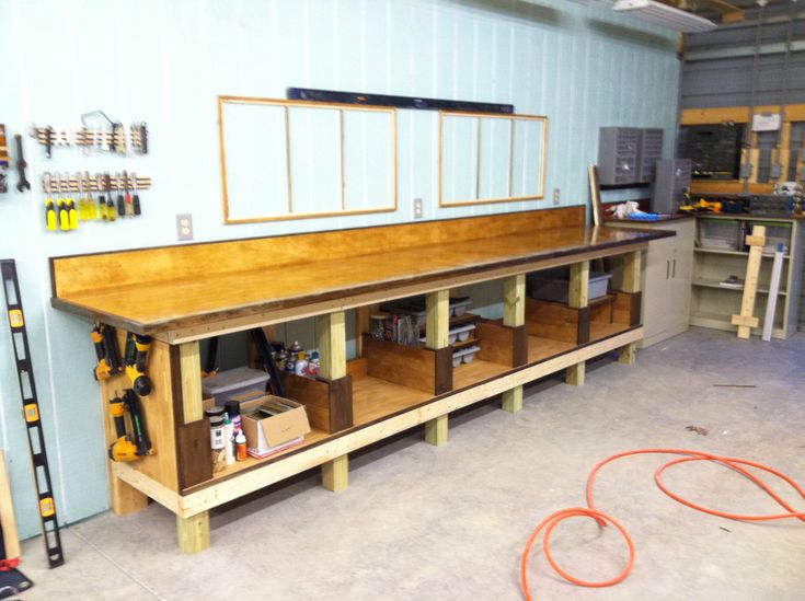 a workbench in a garage with tools on the floor and shelves below it