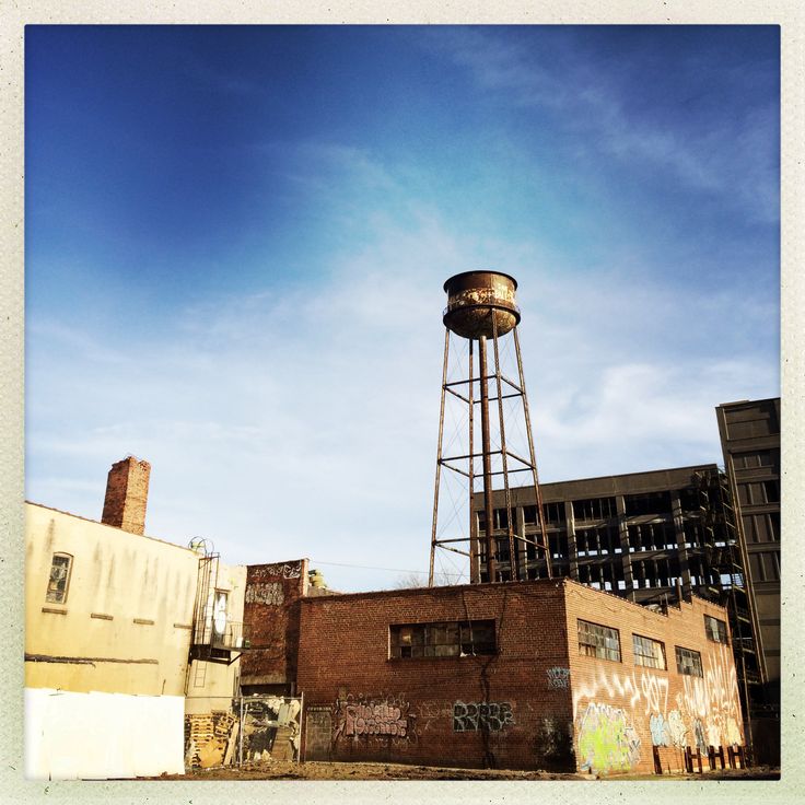 an old brick building with a water tower in the background and graffiti on the walls